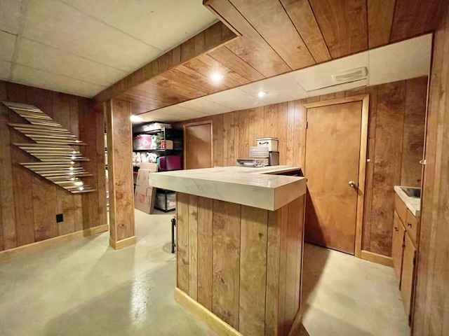 bar with wooden walls, a bar, and finished concrete flooring