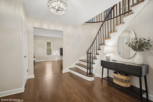 foyer with baseboards, stairs, wood finished floors, and a chandelier