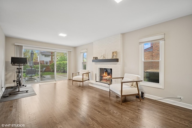 living area with a brick fireplace, baseboards, and wood finished floors