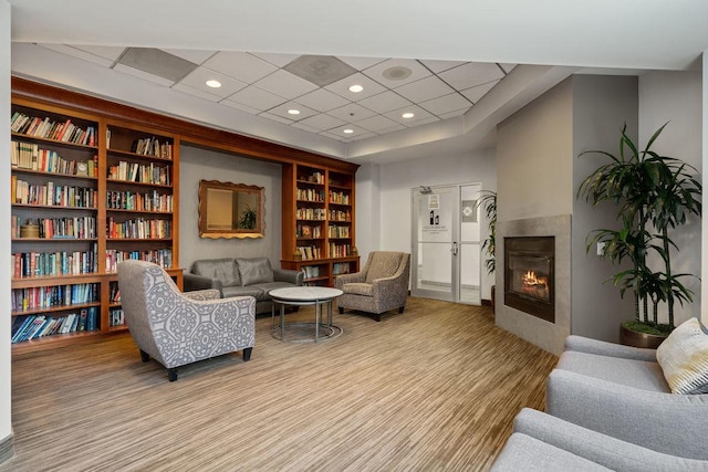 living room featuring built in shelves, a tile fireplace, and a paneled ceiling