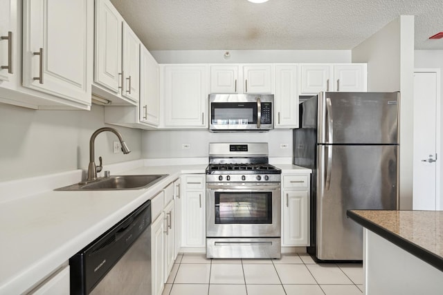 kitchen featuring light tile patterned floors, a sink, white cabinets, and stainless steel appliances