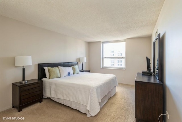 bedroom with baseboards, light carpet, and a textured ceiling