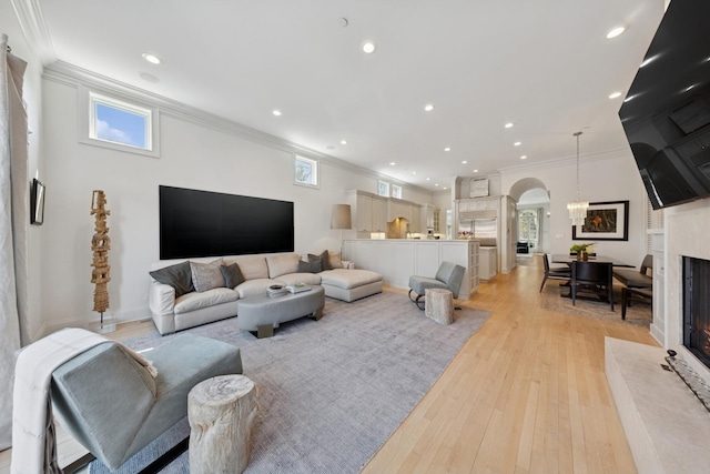 2215 N Lakewood Ave, Chicago, IL 60614 - living room with crown molding, arched walkways, a fireplace with raised hearth, and light wood-type flooring