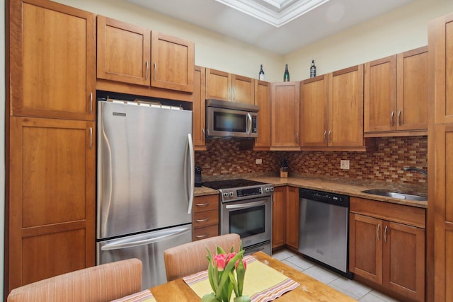 1400 N La Salle St Unit 3N, Chicago, IL 60610 - kitchen featuring stainless steel appliances, a sink, backsplash, light tile patterned floors, and brown cabinets