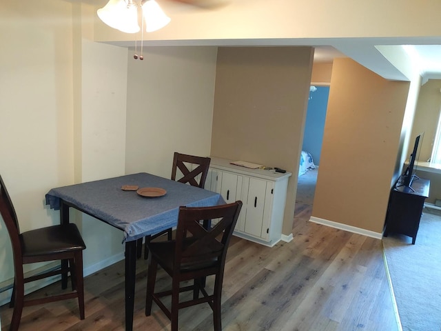 dining area with baseboards, a ceiling fan, and light wood finished floors