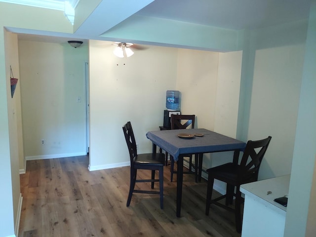 dining space featuring wood finished floors, a ceiling fan, and baseboards