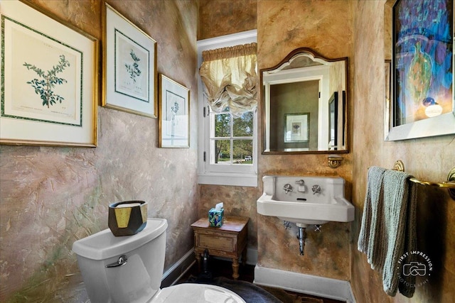 bathroom with a sink, toilet, and baseboards
