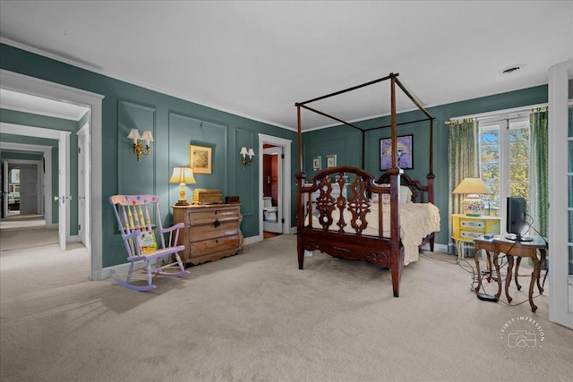 carpeted bedroom with ornamental molding, baseboards, and a decorative wall
