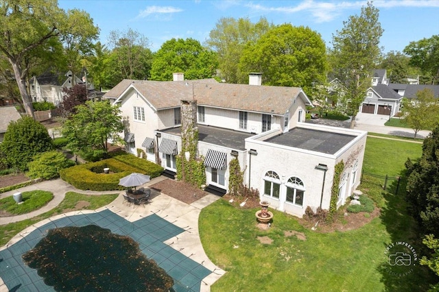 rear view of house with a chimney, a patio area, stucco siding, a covered pool, and a residential view