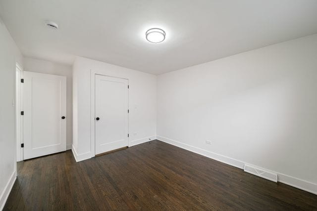 519 E 91st St, Chicago, IL 60619 - unfurnished bedroom featuring dark wood-type flooring, a closet, visible vents, and baseboards