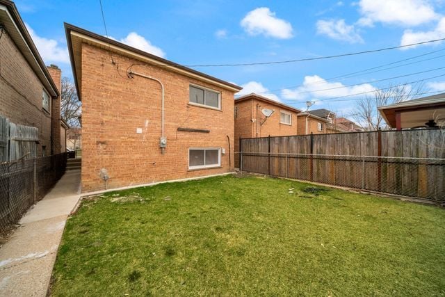 519 E 91st St, Chicago, IL 60619 - back of property with brick siding, a fenced backyard, and a lawn