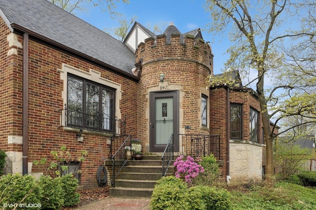 property entrance featuring brick siding and a shingled roof