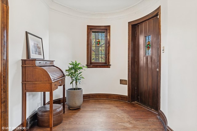 entryway with baseboards, wood finished floors, and ornamental molding