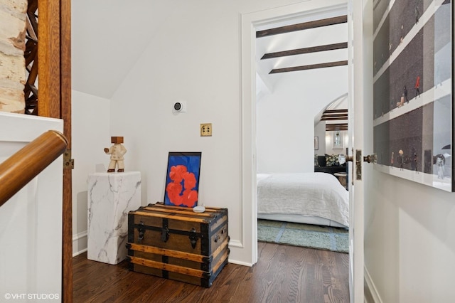 bedroom with wood finished floors, baseboards, vaulted ceiling with beams, and arched walkways