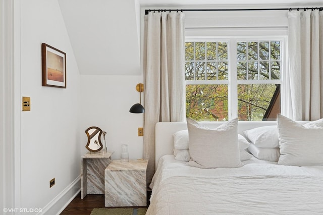 bedroom featuring dark wood-type flooring, vaulted ceiling, and baseboards