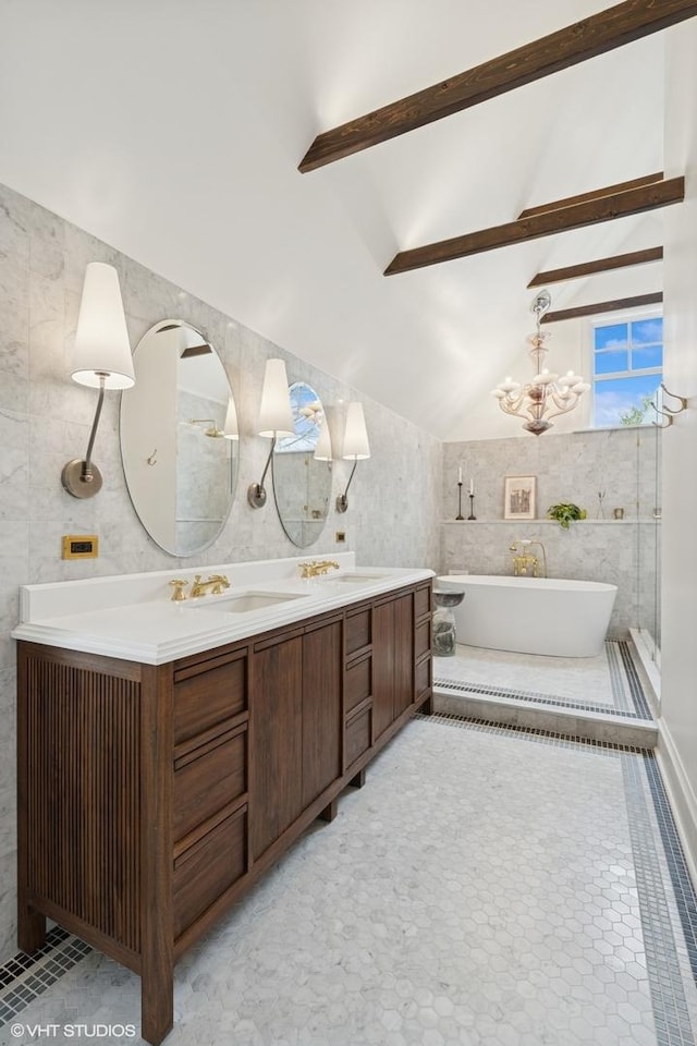 bathroom featuring tile walls, a sink, an inviting chandelier, a freestanding tub, and double vanity