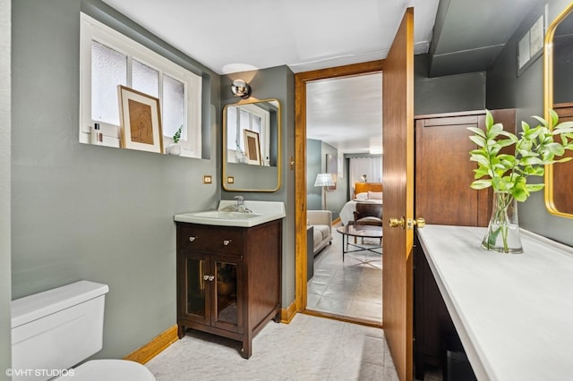 ensuite bathroom featuring toilet, ensuite bathroom, vanity, and baseboards