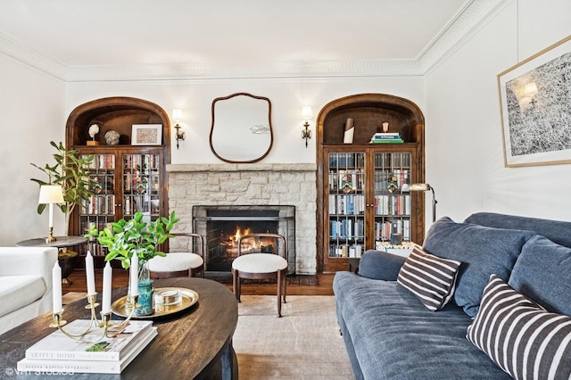 living room featuring ornamental molding, a stone fireplace, and wood finished floors