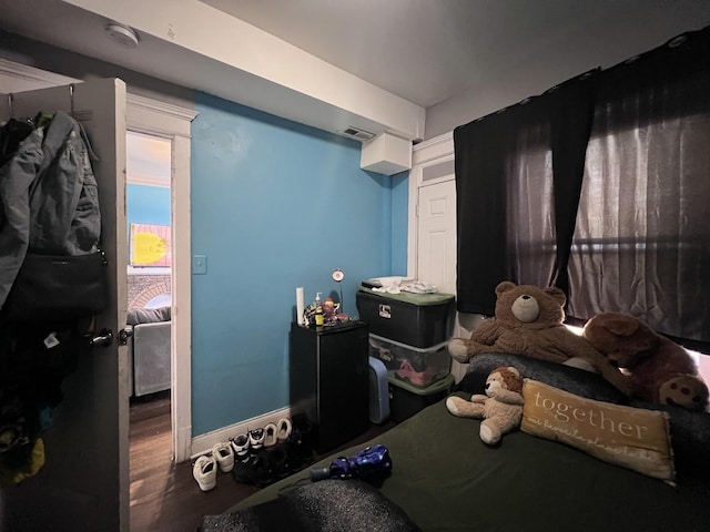 bedroom with baseboards, visible vents, and wood finished floors