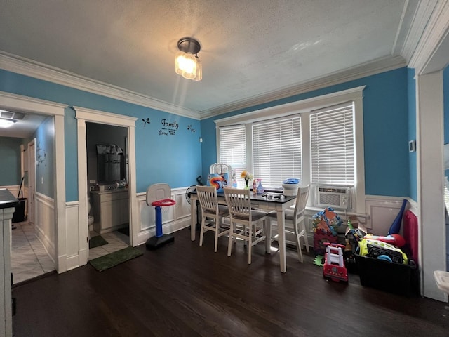 dining space featuring crown molding, wainscoting, and wood finished floors