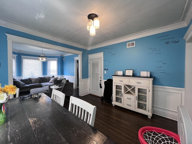 dining space with visible vents, wainscoting, ornamental molding, and dark wood finished floors