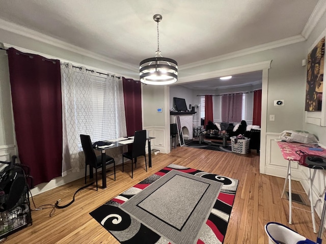 workout room featuring an inviting chandelier, a wainscoted wall, ornamental molding, and a decorative wall
