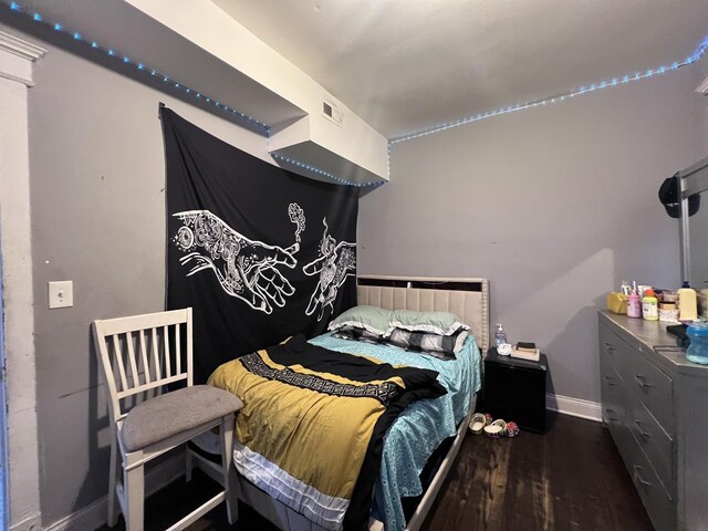 bedroom featuring baseboards, dark wood-style flooring, and visible vents