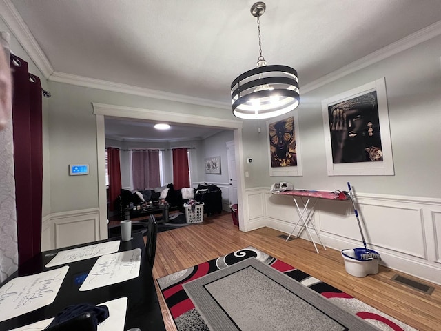 exercise area with visible vents, crown molding, a notable chandelier, a decorative wall, and light wood-style flooring