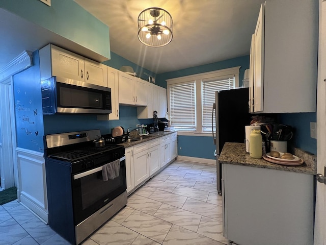 kitchen featuring white cabinetry, appliances with stainless steel finishes, an inviting chandelier, and marble finish floor