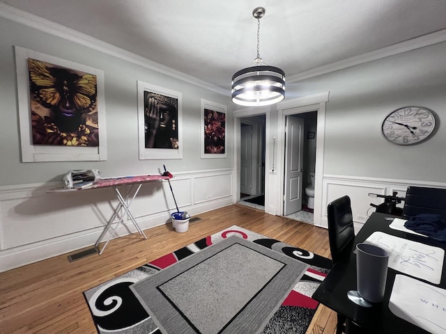 office space featuring crown molding, an inviting chandelier, wainscoting, a decorative wall, and wood finished floors