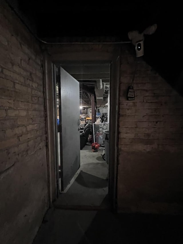 corridor with concrete flooring and brick wall