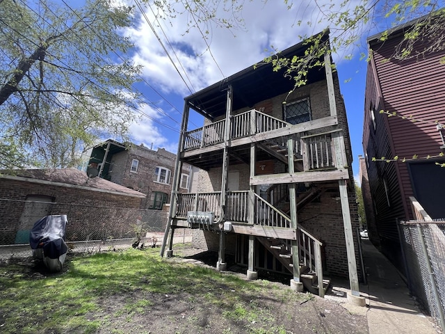 rear view of house with fence, a wooden deck, stairway, and brick siding