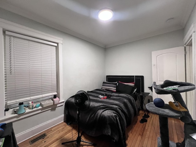 bedroom featuring visible vents, ornamental molding, wood-type flooring, and baseboards