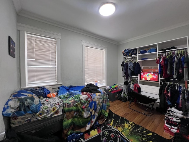 bedroom with ornamental molding and wood finished floors