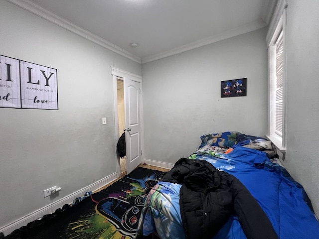bedroom with baseboards, ornamental molding, and wood finished floors