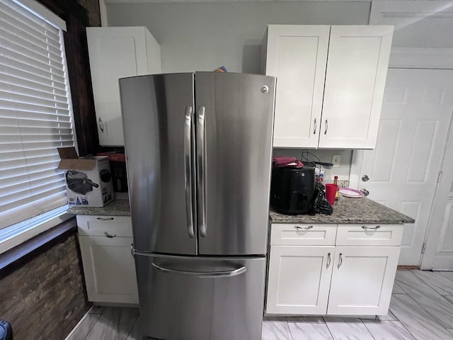 kitchen with freestanding refrigerator, white cabinets, and light stone countertops