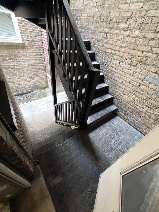 stairway featuring brick wall