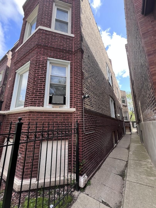 view of side of property with brick siding, a gate, and fence