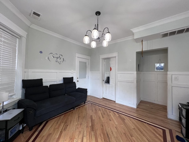 living area with visible vents, light wood-style flooring, and a wainscoted wall