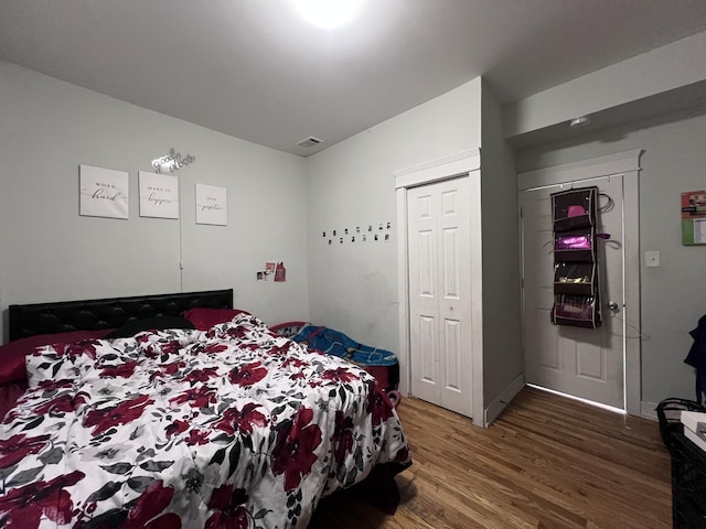 bedroom with a closet, wood finished floors, and visible vents