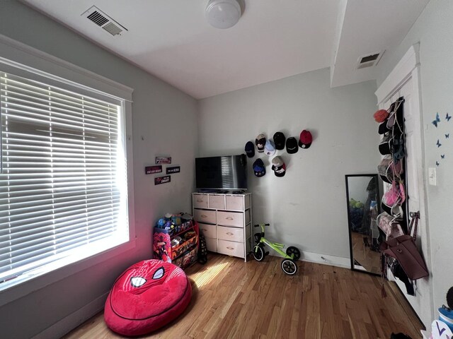 bedroom with baseboards, visible vents, and wood finished floors