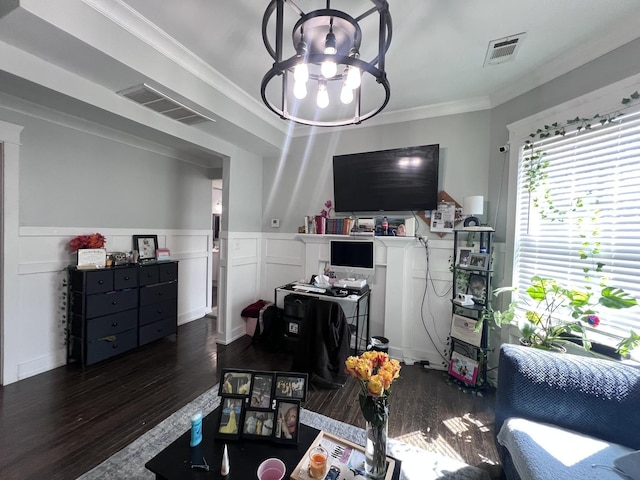 living area with ornamental molding, a chandelier, wood finished floors, and visible vents