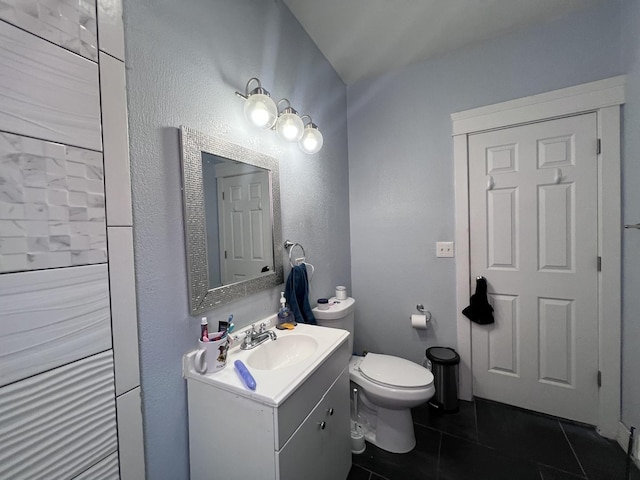 bathroom with tile patterned floors, a textured wall, vanity, and toilet