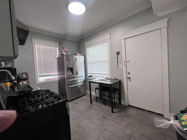 kitchen featuring stainless steel fridge, light tile patterned floors, range hood, and black gas range