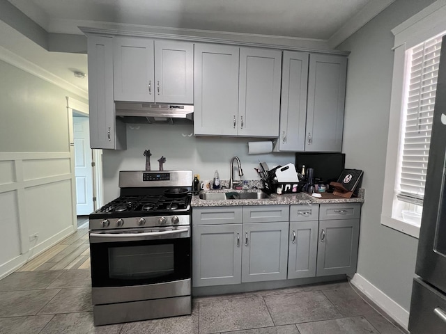 kitchen featuring gray cabinetry, stainless steel gas range, under cabinet range hood, and a sink
