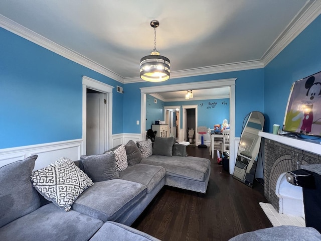 living area featuring crown molding, wainscoting, wood finished floors, and a fireplace