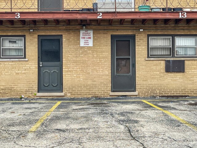 entrance to property featuring uncovered parking and brick siding