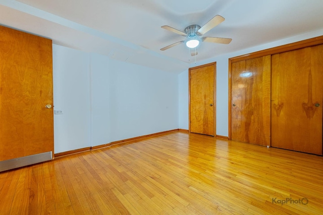 unfurnished bedroom with light wood-style floors, a ceiling fan, baseboards, and two closets