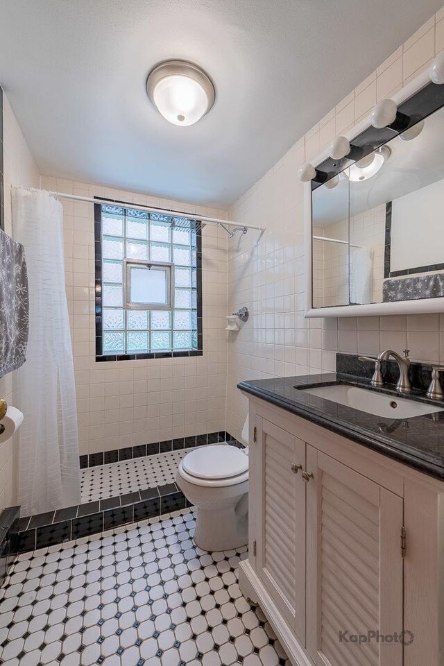bathroom with toilet, tile walls, and tiled shower