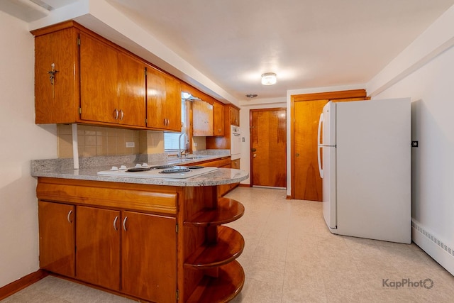 kitchen with a sink, white appliances, light countertops, brown cabinetry, and a peninsula